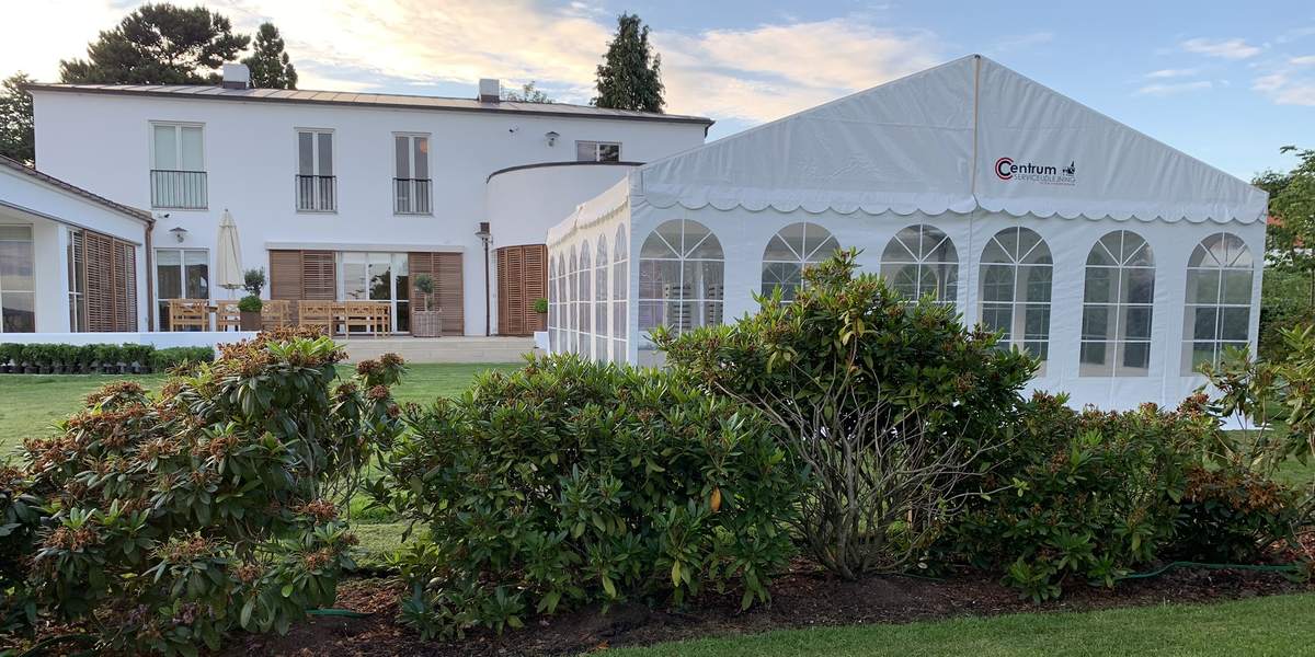 Hvidt festtelt med sprossevinduer stillet op i haven ved en hvid villa